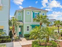 Charming two-story home with light green exterior and well-manicured landscaping, including mature palm trees at 3020 Parrot Head Pl, Kissimmee, FL 34747