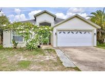 Charming single-story home featuring a white garage door, well-kept lawn, and beautiful flowering shrub in the front yard at 3029 Bransbury Ct, Kissimmee, FL 34747
