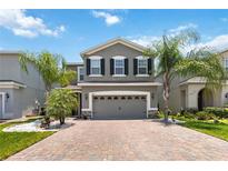 Beautiful two story home with a well manicured lawn and a brick driveway with palm trees flanking the home at 3883 Crawley Down Loop, Sanford, FL 32773