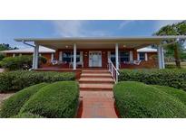Charming brick home with inviting front porch, white columns, swings, and manicured landscaping at 4895 Cr 134B, Wildwood, FL 34785