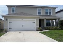 Two-story home featuring an attached two-car garage and a covered front porch at 5350 Pine Lilly Dr, St Cloud, FL 34771