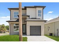 A contemporary two-story home with a gray exterior, a one-car garage, and a well-manicured lawn at 811 E Mcdonald Ave, Eustis, FL 32726
