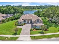 Beautiful home exterior with a paver driveway, lush landscaping, and a scenic lake view in the background at 1017 Parkside Pointe Blvd, Apopka, FL 32712