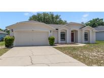 Charming single-story home featuring a two-car garage, manicured lawn, and a welcoming red front door at 160 Conch Dr, Kissimmee, FL 34759