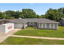 Charming single-story home with well-manicured lawn, sidewalk, and a PODS moving and storage container in the driveway at 217 Spencer St, Orlando, FL 32839