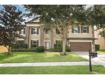 Charming two-story home with a well-manicured lawn, mature trees, and a two-car garage at 319 Morning View Dr, Winter Garden, FL 34787