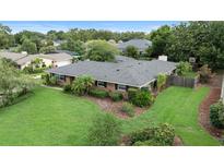 An aerial view of a brick house with a well-manicured lawn, mature trees, and an expansive roof at 1271 Old Mill Rd, Orlando, FL 32806