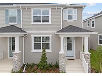 Charming two-story townhome featuring stone accents, a covered entrance, and manicured landscaping at 1315 Tarflower Dr, Winter Springs, FL 32708