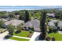 A well-maintained home featuring a lush lawn and mature landscaping, nestled near a tranquil lake at 13631 Via Roma Cir, Clermont, FL 34711