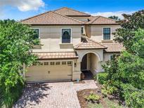 Charming two-story home featuring a red tile roof, a brick driveway and an attached two-car garage at 1478 Moon Valley Dr, Davenport, FL 33896