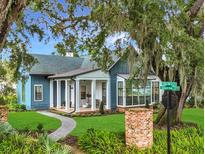 Charming home with blue siding, white trim, covered front porch, beautiful landscaping and mature trees at 15198 E Oakland Ave, Winter Garden, FL 34787