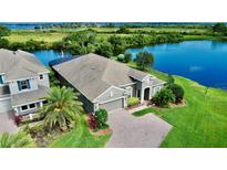 Stunning exterior view of home featuring a brick driveway, lush landscaping, and beautiful waterfront views at 15510 Lake Burnett Shore Ct, Winter Garden, FL 34787