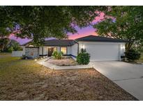 Charming single-story home with a stone accent wall, well-lit walkway, lush landscaping, and a two-car garage at 16190 Sw 16Th Ct, Ocala, FL 34473