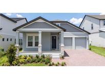 Charming single-Gathering home featuring a light blue exterior, a two-car garage, and a beautifully landscaped front yard at 16489 Silver Brook Way, Winter Garden, FL 34787