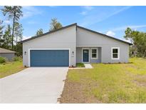 Charming single-story home featuring a modern design, blue garage door, and well-maintained lawn at 2506 Sw 158Th Lane Rd, Ocala, FL 34473