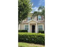 Inviting tan home featuring a covered porch, brown shutters, and manicured landscaping, perfect for comfortable living at 3229 Cupid Pl, Kissimmee, FL 34747
