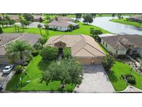 Stunning aerial view of a home with a tile roof, lush landscaping, and a serene lake backdrop at 453 Sorrento Rd, Kissimmee, FL 34759