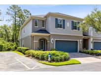 Charming two-story townhome featuring a blue garage door, blue shutters, and well-manicured landscaping at 707 Evening Sky Dr, Oviedo, FL 32765