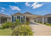 Charming single-story home with tan siding, blue shutters, and a well-manicured front yard and an attached covered carport at 747 Louise Ln, The Villages, FL 32163