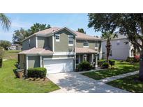 Charming two-story home featuring a two-car garage, lush lawn, and mature trees at 8518 La Isla Dr, Kissimmee, FL 34747