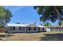 Charming home featuring a metal roof, stone accents, and mature trees in a well-manicured front yard at 11624 Ocklawaha Dr, Leesburg, FL 34788