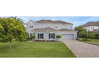 Charming two-story home features a manicured lawn, paver driveway, and a welcoming facade at 16086 Johns Lake Overlook Dr, Winter Garden, FL 34787