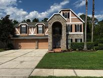 Charming two-story home with stone accents, black shutters, a well-manicured lawn, and a three car garage at 2143 Autumn View Dr, Orlando, FL 32825