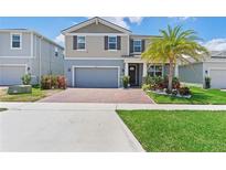Charming two-story home with a brick driveway, two-car garage and well-manicured lawn, enhanced with a palm tree at 2227 Blue Salvia St, Clermont, FL 34711