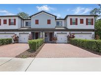 Charming townhome with red shutters, a brick paver driveway, and meticulously maintained landscaping at 328 Cedar Bark Ln, Sanford, FL 32771