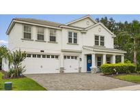 Two-story home featuring a 2 car garage, blue front door, and gray brick driveway at 8811 Bally Neal Loop, Davenport, FL 33896