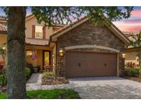 Charming home featuring a stone facade, a two-car garage, and a beautifully landscaped front yard at 10430 Belfry Cir, Orlando, FL 32832