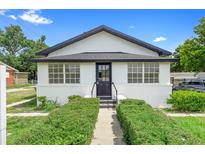 Charming white stucco bungalow featuring black trim, symmetrical windows, and manicured front hedges at 161 Bolender Rd, Auburndale, FL 33823