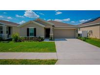 Charming single-Gathering home with a well-maintained lawn, an attached two-car garage, and manicured landscaping at 214 Brave Rd, Davenport, FL 33837