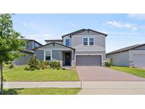 Charming two-story home with gray siding, manicured lawn, brick driveway and two-car garage at 5291 Meredrew Ln, St Cloud, FL 34771