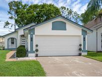 A bright white two-car garage with a blue trim, potted plants on the side, and a well-kept lawn in front at 5729 Norman H Cutson Dr, Orlando, FL 32821