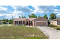 Charming single-story home with a well-maintained lawn, mature trees, and a two-car garage on a sunny day at 7135 Sw 129Th St, Ocala, FL 34473