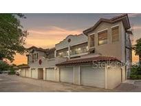 View of a multi-story home with an attached garage featuring a red tile roof and stucco walls at 7842 Holiday Isle Dr # 102, Belle Isle, FL 32812