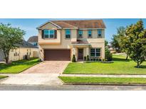 Charming two-story home with a well-manicured lawn and a brick driveway leading to an attached two-car garage at 15058 Sawgrass Bluff Dr, Winter Garden, FL 34787