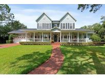 Charming two-story home boasts a large front porch, green lawn, and beautiful curb appeal at 1550 Bluewater Run, Chuluota, FL 32766