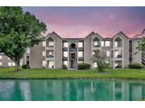 Beautiful exterior view of a waterfront apartment building on a grassy lawn during a colorful dusk at 4740 Walden Cir # 28, Orlando, FL 32811