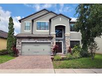 Charming two-story home with stone accents, landscaped yard, and brick-paved driveway at 5107 Appenine W Loop, St Cloud, FL 34771