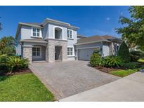 Charming two-story home with a paver driveway, stone accents, well-manicured landscaping and blue skies at 5365 Bowman Dr, Winter Garden, FL 34787
