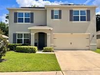 Charming two-story home featuring a well-manicured lawn and a convenient two-car garage at 6780 Coral Berry Dr, Mount Dora, FL 32757