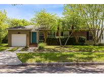 Charming home featuring a manicured lawn, palm trees, and a bright blue front door at 815 W Yale St, Orlando, FL 32804