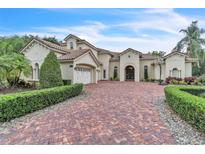 Elegant home with a large brick driveway, manicured landscaping, and a three-car garage at 9729 Lake Hugh Dr, Gotha, FL 34734