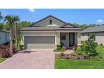 Charming home featuring a brick driveway, attached garage, and well-manicured lawn with colorful flowers at 1392 Lombardi Ct, Kissimmee, FL 34759