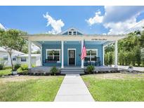 Charming blue cottage-style home with a welcoming front porch and well-manicured lawn at 141 W Main St, Lake Helen, FL 32744