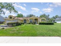 Inviting one-story home with lush front lawn, charming landscaping, and attached two car garage at 1910 Palm View Dr, Apopka, FL 32712