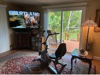 Cozy room with an exercise bike, TV, and sliding glass door to the outdoor deck at 2808 Manatee Rd, Tavares, FL 32778