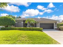 Charming single-story home features a well-manicured lawn, trimmed hedges, and a two-car garage at 5335 Bay Side Dr, Orlando, FL 32819